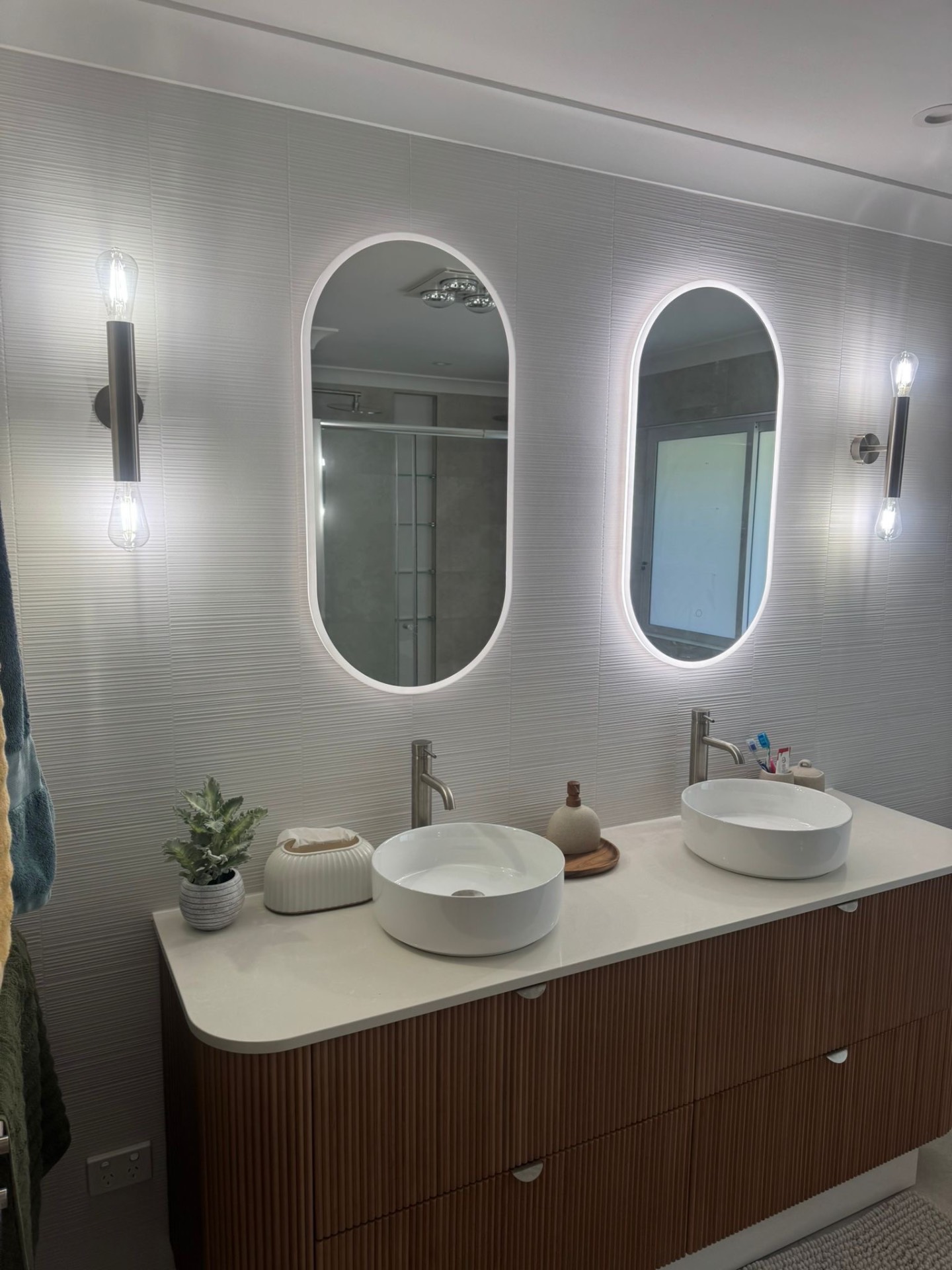 Twin oval mirrors above a fluted timber double vanity